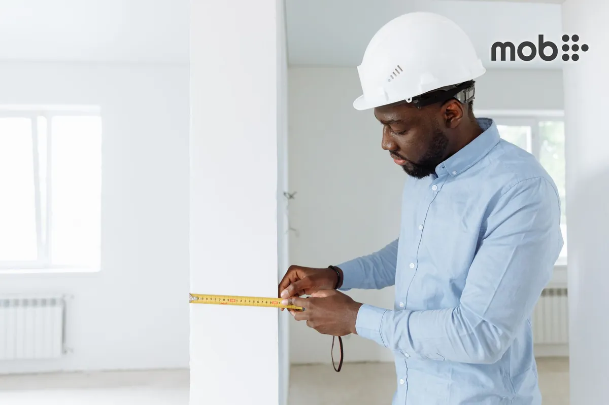 Plumber measuring the inlet centres of an exposed bathroom wall mixer
