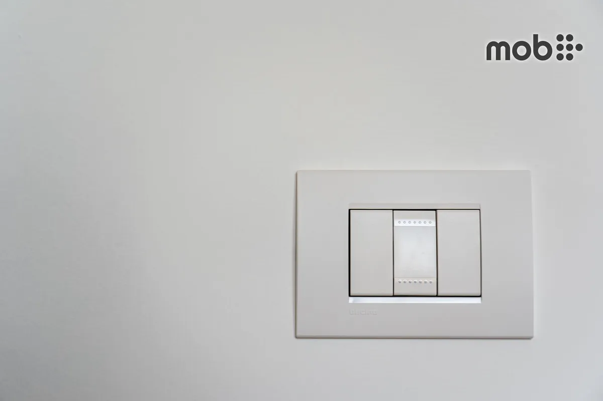 Electrician comparing a replacement modular switch with the existing plate and frame
