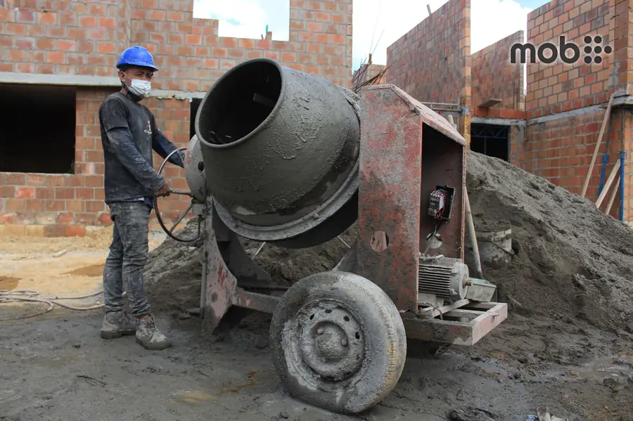Construction worker inspecting a cement bag for authenticity and freshness at a building site.